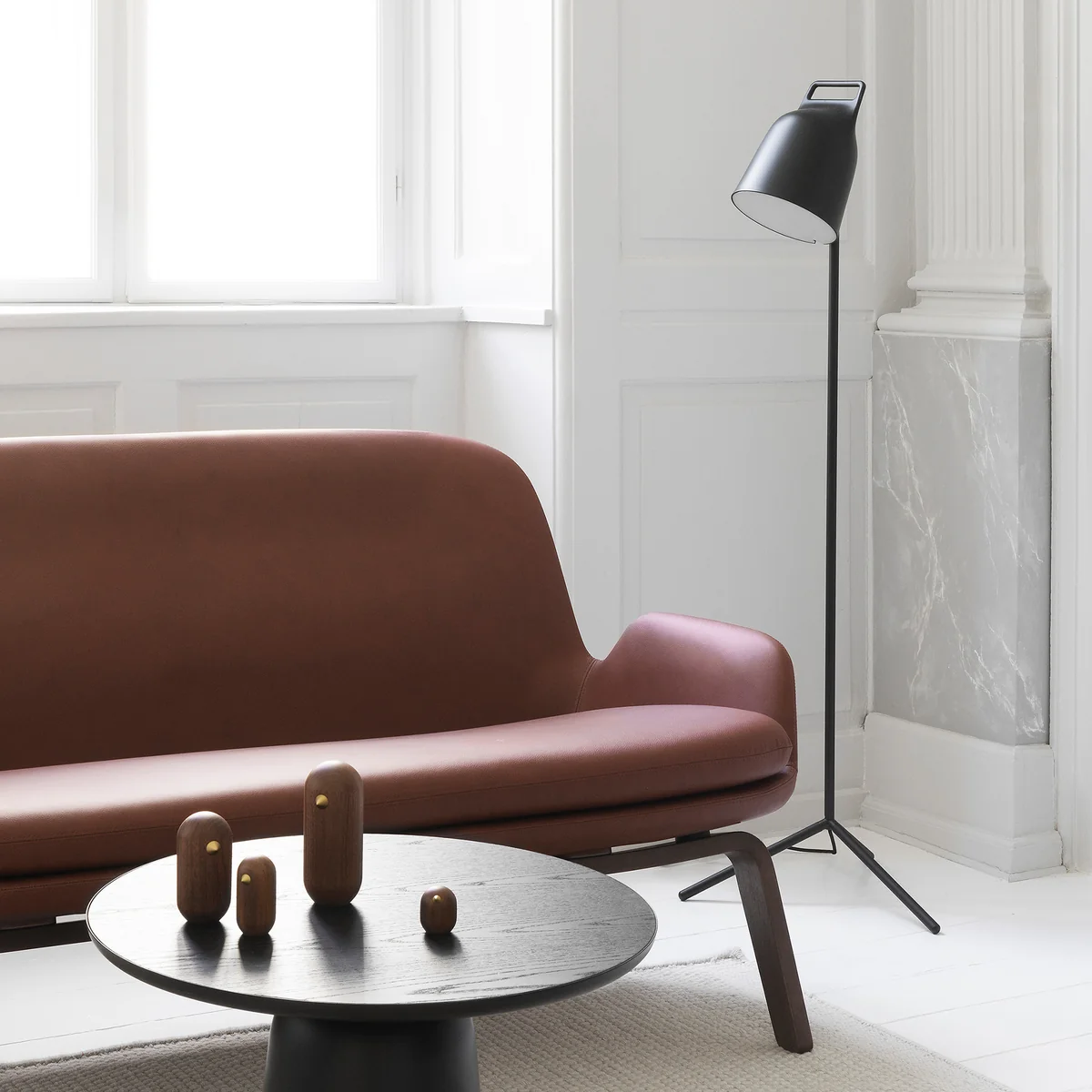 De Stage LED-vloerlamp van Normann Copenhagen naast een bruine lederen bank.