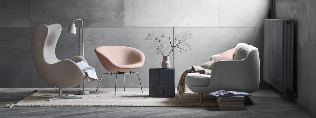 De Cosy Lune 2-zitsbank van Fritz Hansen met de bijpassende Pot chair in zacht grijs en roze tinten. Een moderne woonkamer ambiance voor een grijze muur.