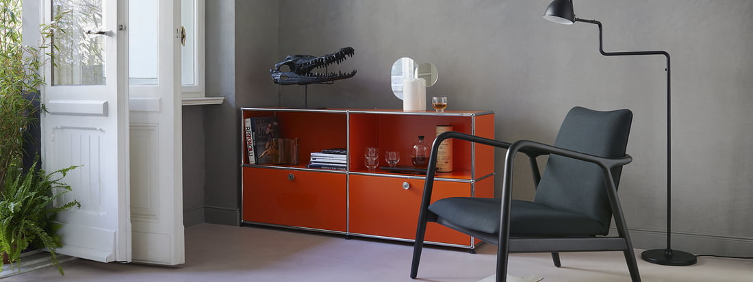 USM Haller - Fabrikantenprogramma - woonkamer - Sideboard M - oranje - fauteuil - staande lamp - boeken - glazen - witte deuren - planten - sfeer