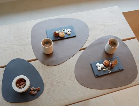 De Curve placemat van LindDNA in de ambiance-optiek: De placemat is gemaakt van gerecycled leer en beschermt de eettafel optimaal tegen krassen en vlekken.