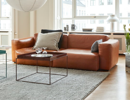 De Mags Soft Sofa van Hay in de ambiance-optiek: de hoogwaardige leren bank in cognac laat zich perfect combineren met beige kussens en een grijs tapijt.
