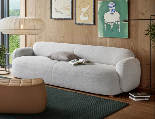 De Mags Soft Sofa van Hay in de ambiance-optiek: de hoogwaardige leren bank in cognac laat zich perfect combineren met beige kussens en een grijs tapijt.