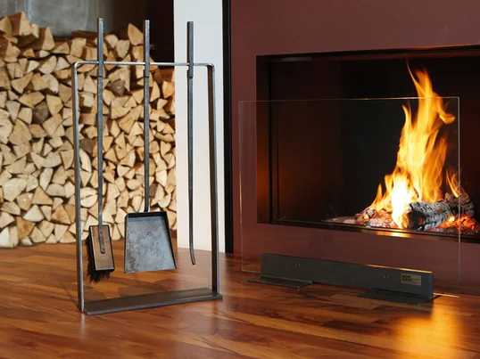 Met de helpende handen staat het gereedschap van artepuro, met lange steelharken, bezems en schoppen op een smal stalen frame van geolied zwart staal.