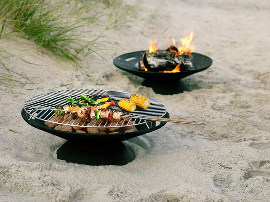 De Helios vuurplaats van Skagerak creëert een gezellige sfeer en stemming in de tuin. Hij is ook perfect om te barbecueën met de bijbehorende roestvrijstalen grill.