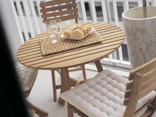 Houten tuinmeubelen geven het balkon een rustieke uitstraling. De Vendia tafel met stoelen van Skagerak is de perfecte plek voor een heerlijk openlucht ontbijt.