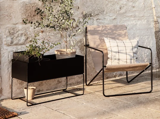 De Desert Chair van ferm Living in de sfeerweergave: samen met de Plant Box creëert de filigraan stoel een gezellige sfeer om te ontspannen op het terras.