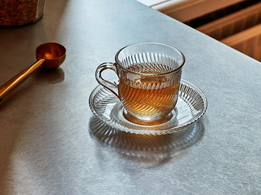 De klassieke Pirouette cup met de bijpassende schotel van HAY overtuigt door het transparante materiaal en het omringende wervelende ribpatroon.