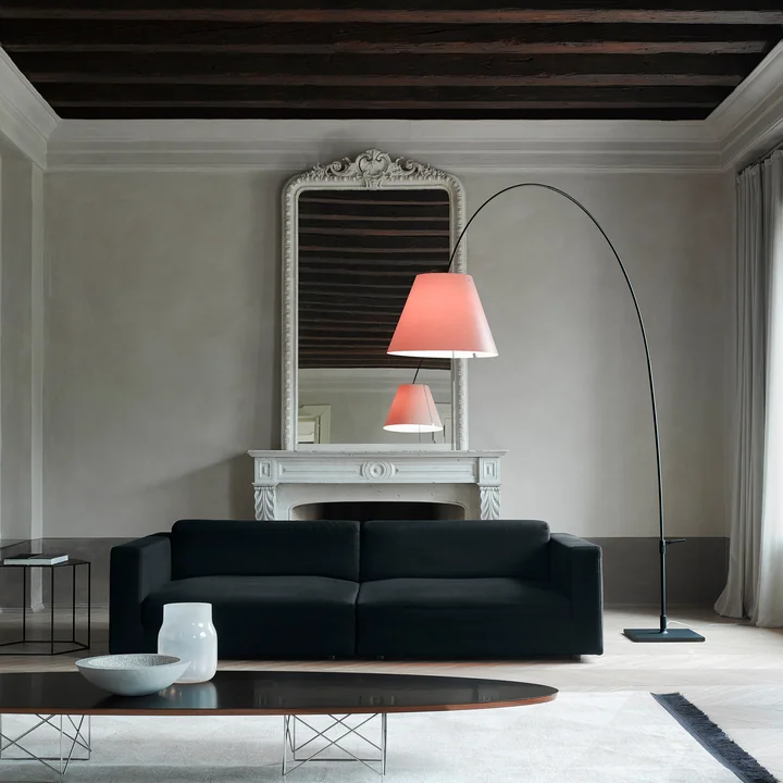 De Lady Costanza vloerlamp van Luceplan boven een bank in een stijlvolle woonkamer