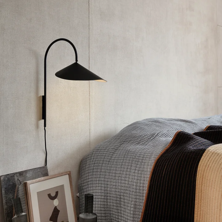 Arum Wandlamp in zwart van Ferm Living naast het bed