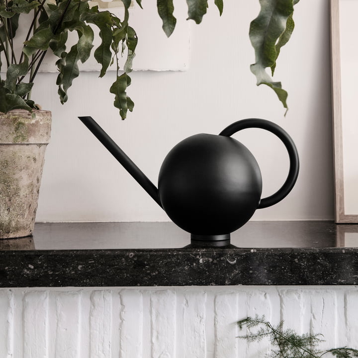 Orb gieter uit ferm Living naast een plant