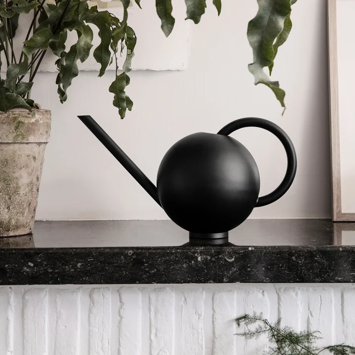 Orb gieter uit Ferm Living naast een plant