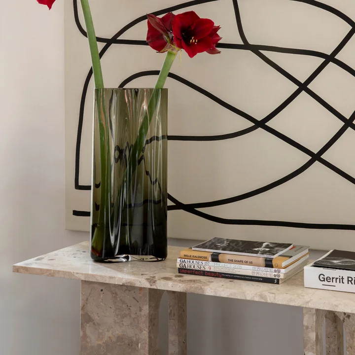 De Androgyne Lounge Table van Audo in combinatie met een groot kunstwerk aan de muur, een vaas en boeken.