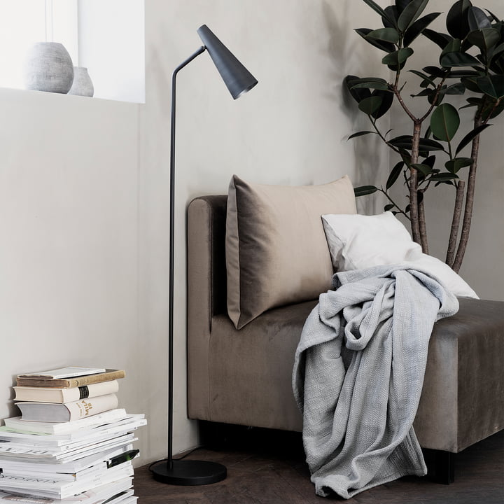 De vloerlamp Precise, mat zwart van House Doctor naast de fauteuil in de woonkamer