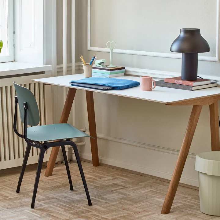 De Revolt Chair, zwart / petrol groen van HAY op een bureau