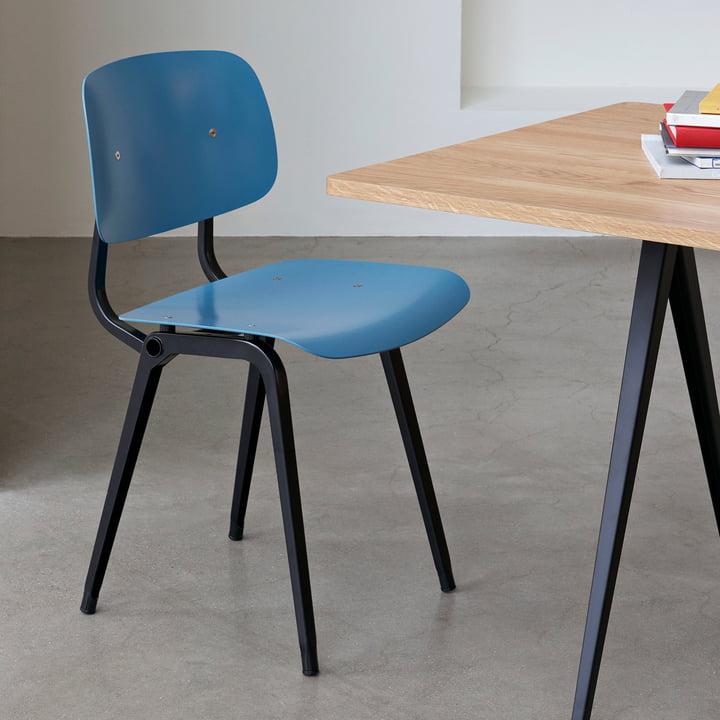 De Revolt Chair, zwart / azuurblauw van Hay op een houten tafel met zwarte poten