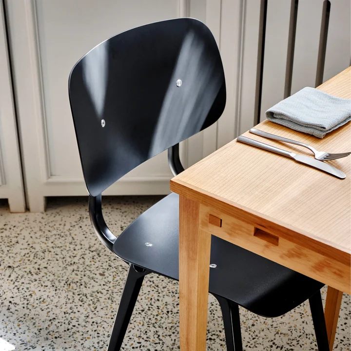 De Revolt Chair, zwart / zwart van HAY op een houten eettafel