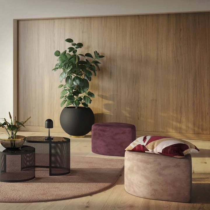 De Globe bloempot van AYTM met een hoge kamerplant naast de Stilla poefjes van AYTM