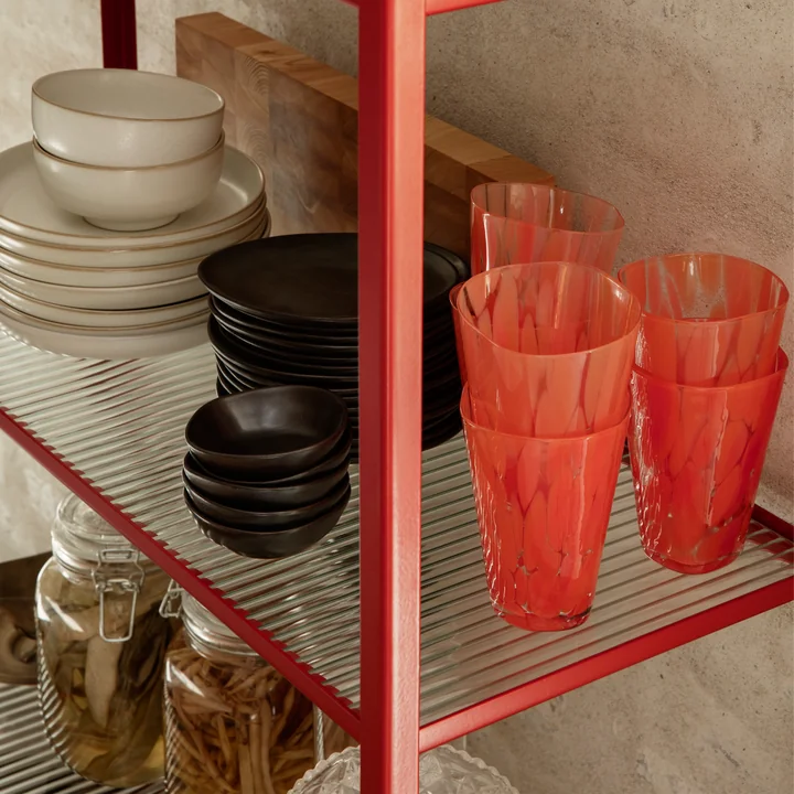 De Casca drinkglas van fermenteren Leven in poppy red op een wandplank naast ander serviesgoed