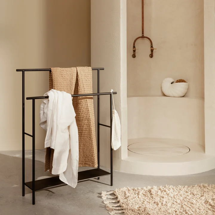 De Dora handdoekhouder van Ferm Living met handdoeken naast de stenen douche