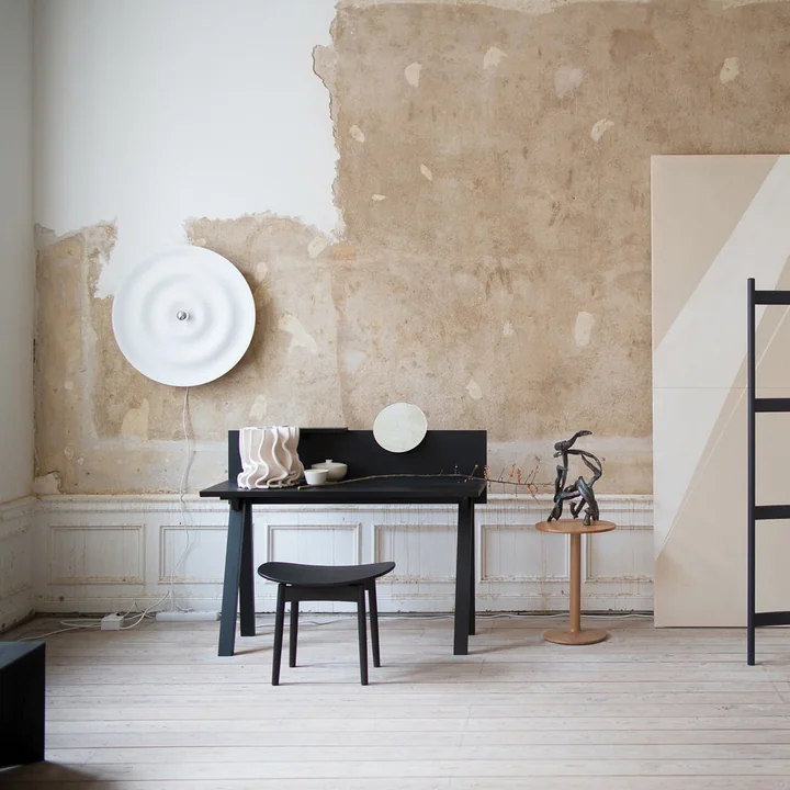 De Alma Wand- en plafondlamp van Wästberg in wit in een lichte studio met zwart bureau en stoel