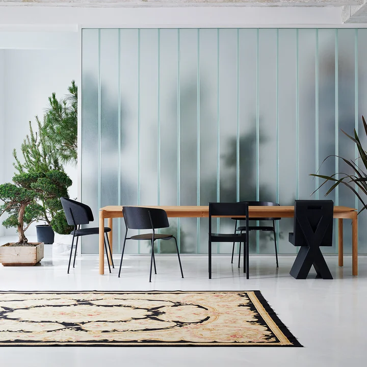 Dining Chair OUT Objekte unserer Tage De Wagner uit in antraciet aan een grote houten eettafel naast andere donkere stoelen