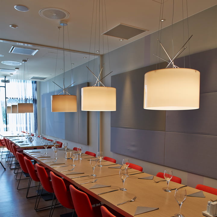 De Ray hanglampen van Flos boven een lange tafel in een restaurant.