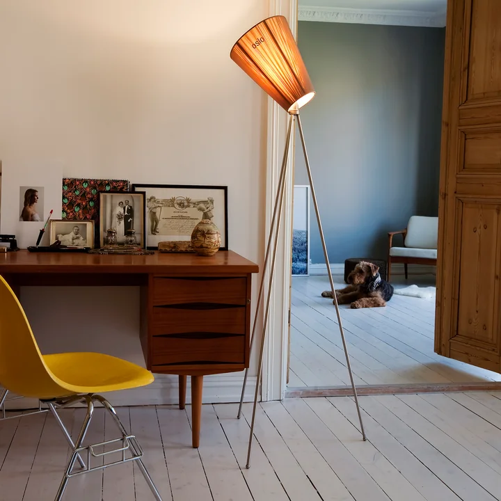 De Oslo Wood vloerlamp van Northern naast een antiek bureau met een gele stoel.