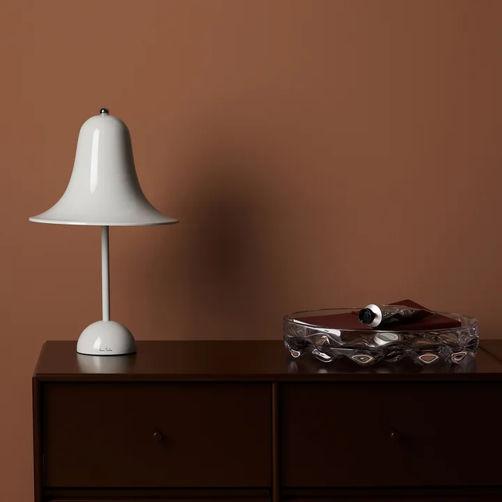 De mintgrijze Pantop tafellamp van Verpan op een donker houten dressoir