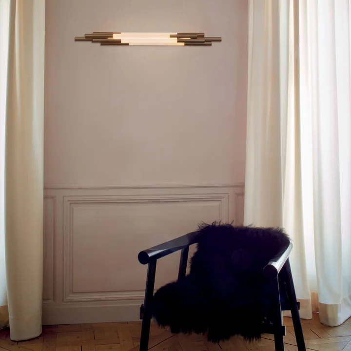 De Org LED wandlamp van DCW op de woonkamermuur boven een fauteuil