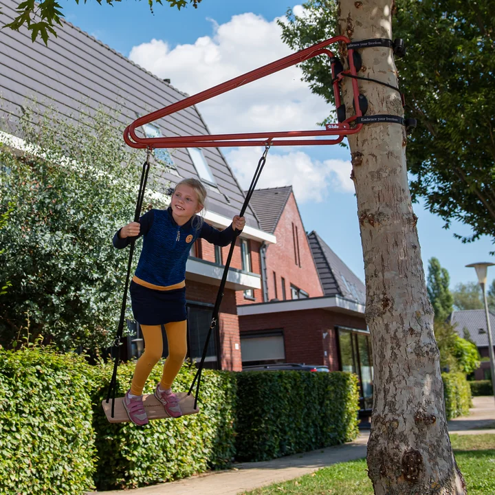 De Swing schommel van Weltevree op een boom in een buurt van huizen.