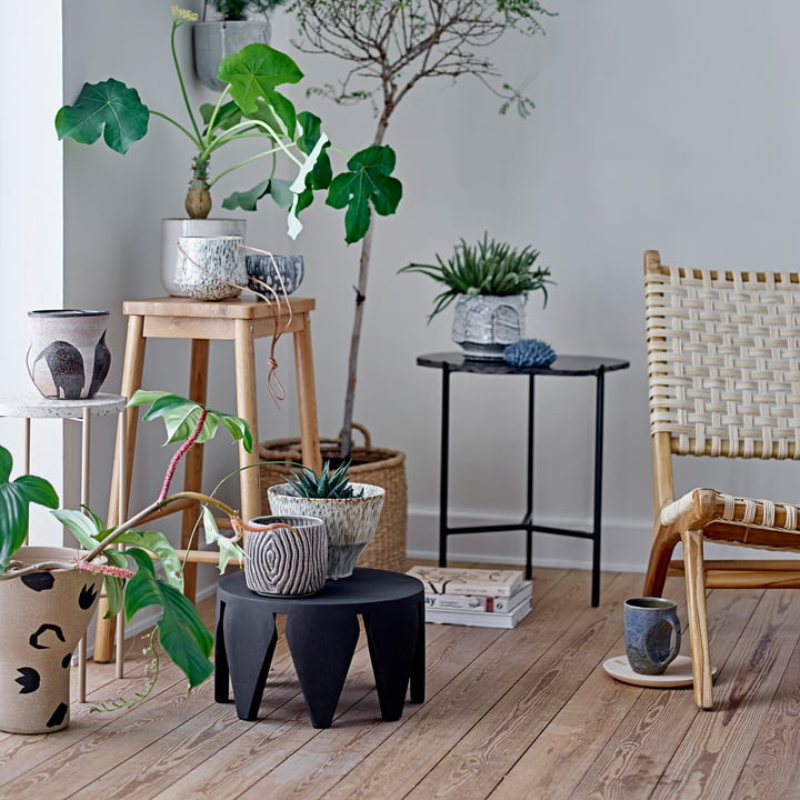 De Atena & Hena bloempot van Bloomingville op een bijzettafel naast vele planten.