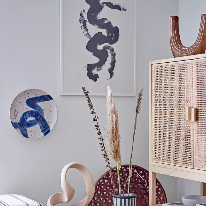 De Oscar wandplaat van Bloomingville op de muur naast andere decoratieve objecten