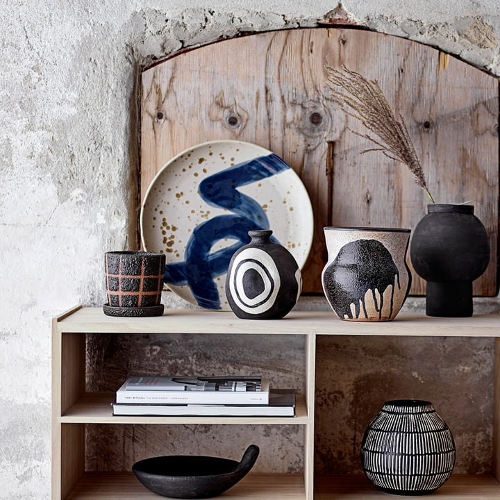 De Oscar wandplaat van Bloomingville op een houten dressoir naast vazen en decoratieve objecten.