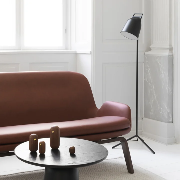 De Stage LED-vloerlamp van Normann Copenhagen naast een bruine lederen bank.