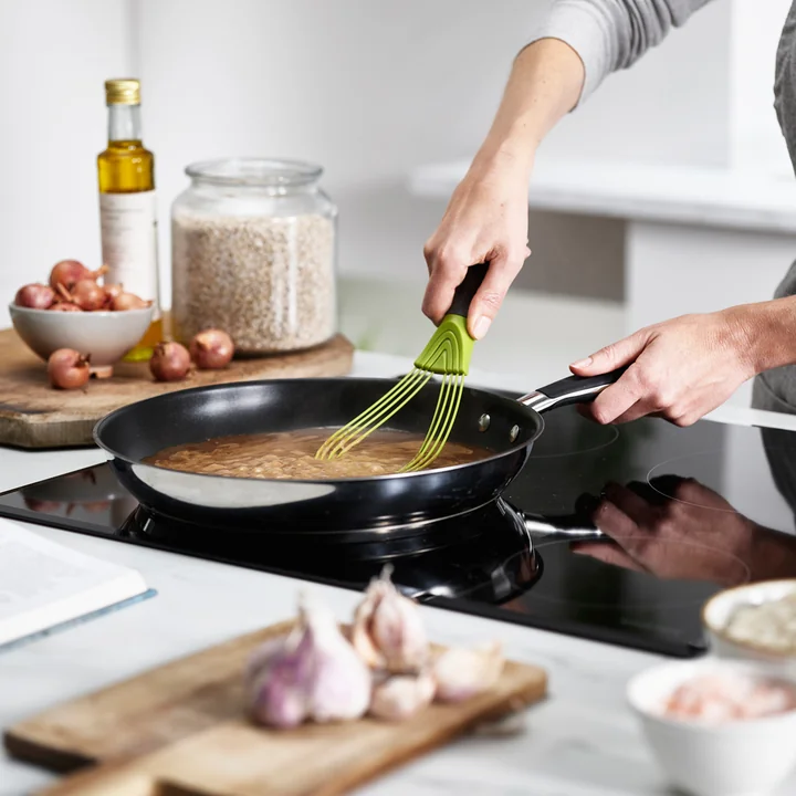 De flat Twist Klopper van Joseph Joseph bij het roeren van een saus
