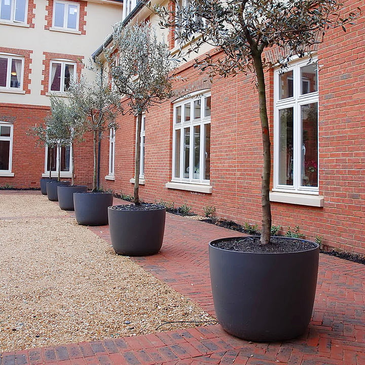 De Kyoto plantenpot van Eternit op de binnenplaats van een groot gebouw.