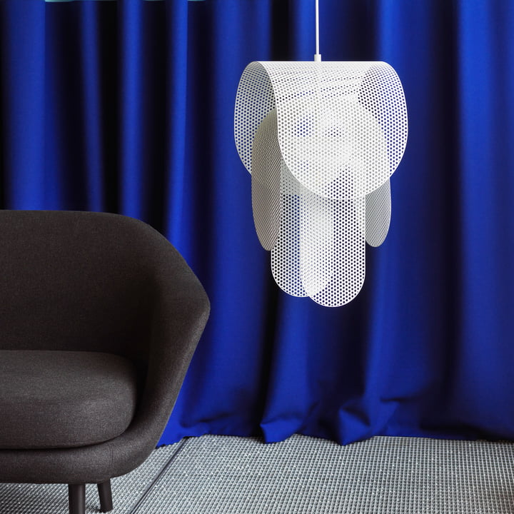 De Superpose hanglamp van Normann Copenhagen naast een zwarte fauteuil