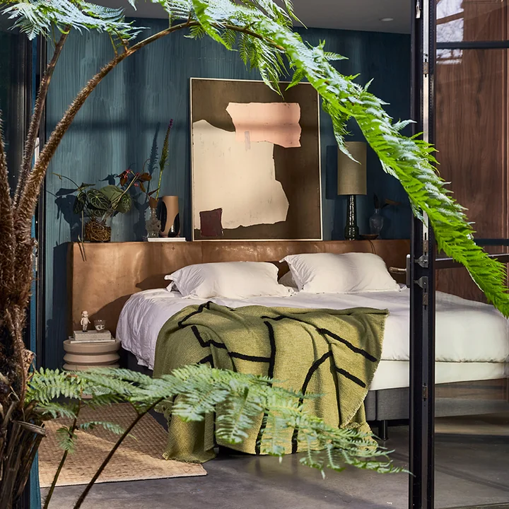 Het jute tapijt naast een bed met een deken van HKliving