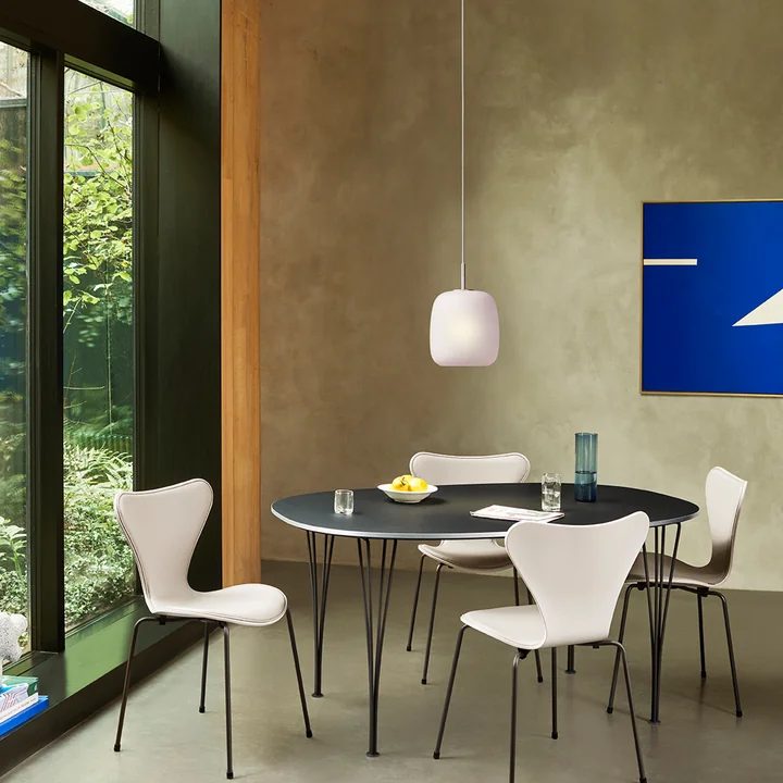 De roze Maluma H350 hanglamp van Fritz Hansen boven de zwarte eettafel