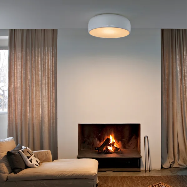 De Smithfield Pro plafondlamp van Flos in de woonkamer boven een beige bank met open haard